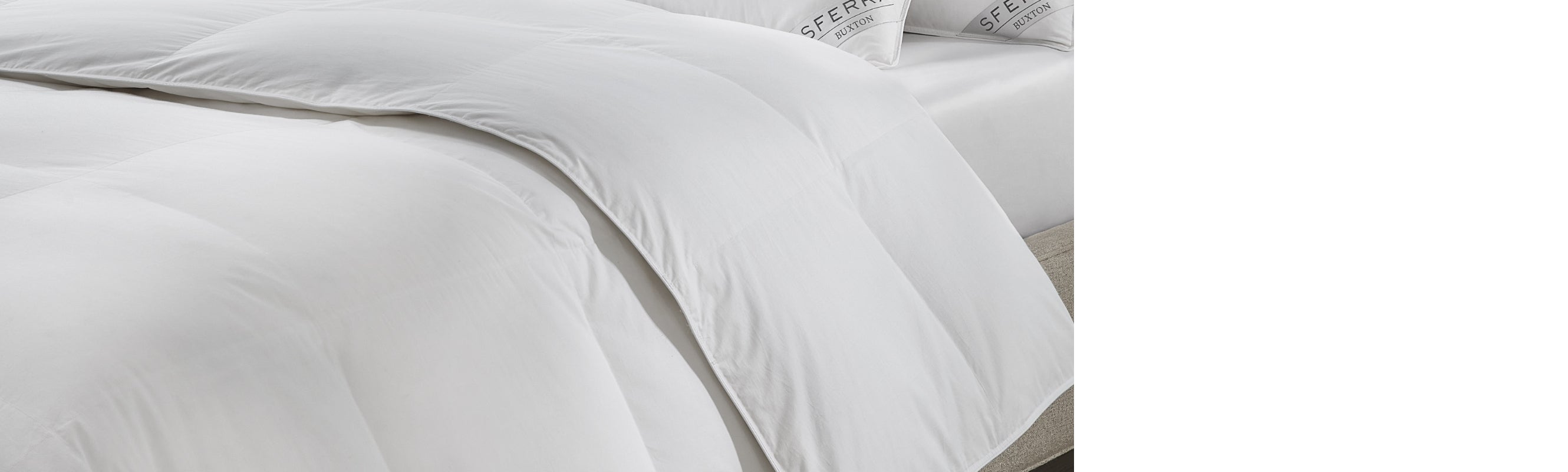 A SFERRA white goose down duvet draped over a bed.